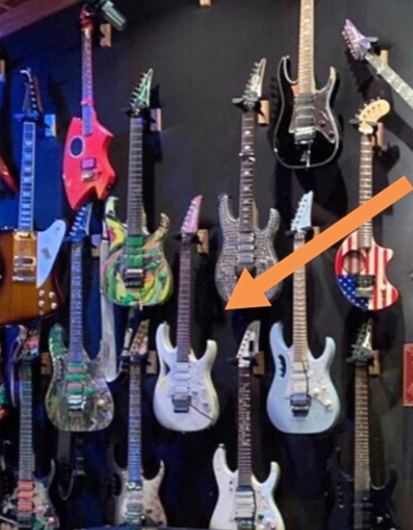 A Modern Primitive pendurada entre as guitarras da coleção de Steve Vai, indicada por uma seta