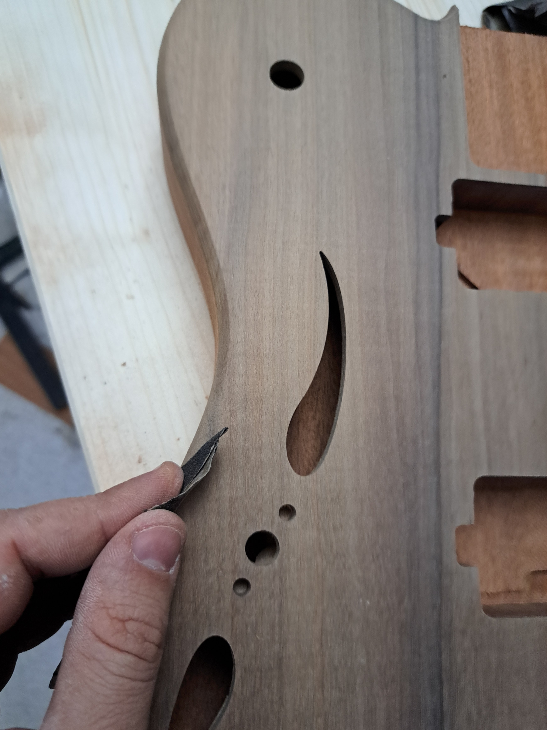 An f-hole being finished with a scraper on a semi-hollow walnut body