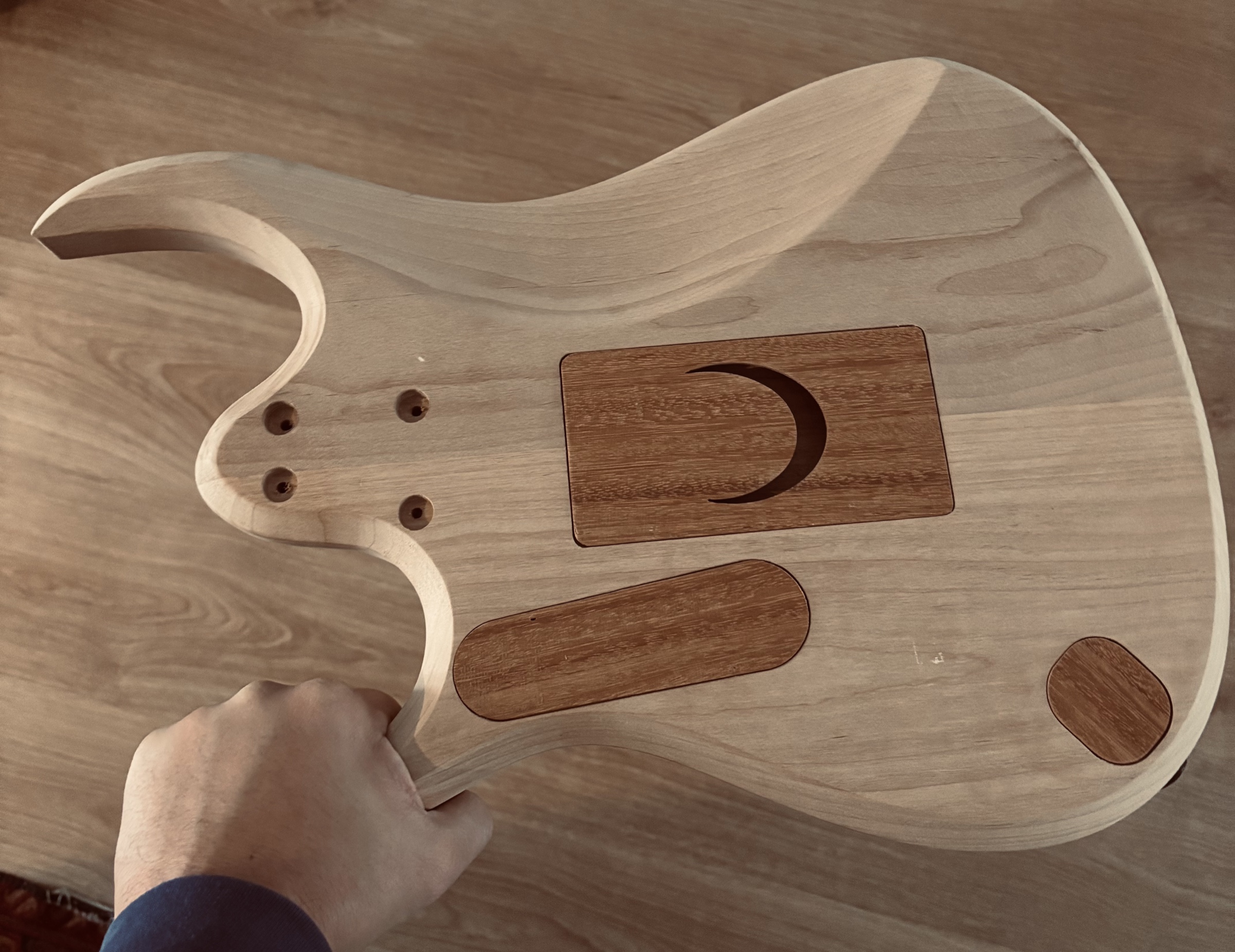 The back of a raw body held in one hand, with wooden cavity covers and a carved moon