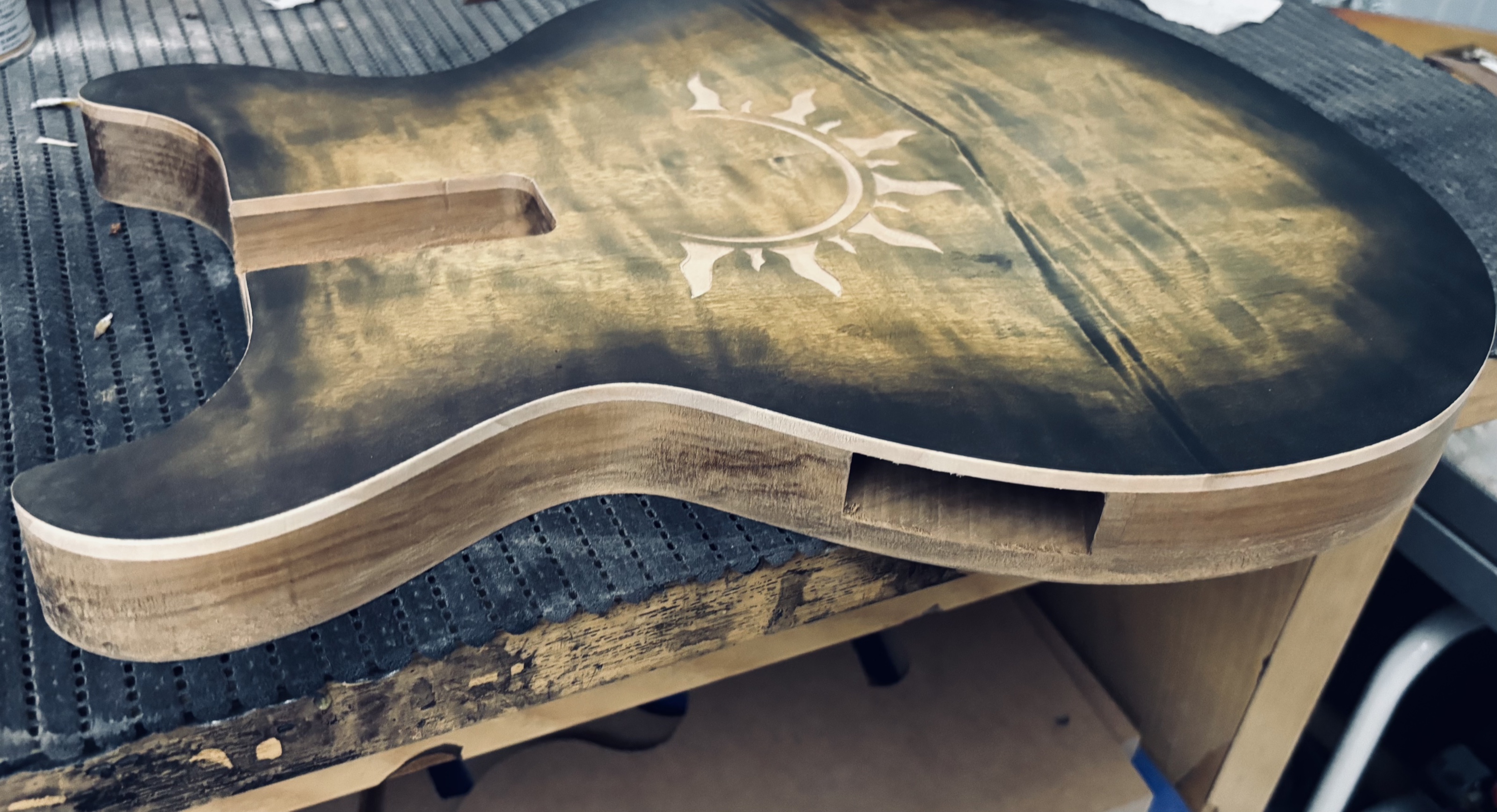 A semi-hollow body with a sun inlaid into the top, still being worked on
