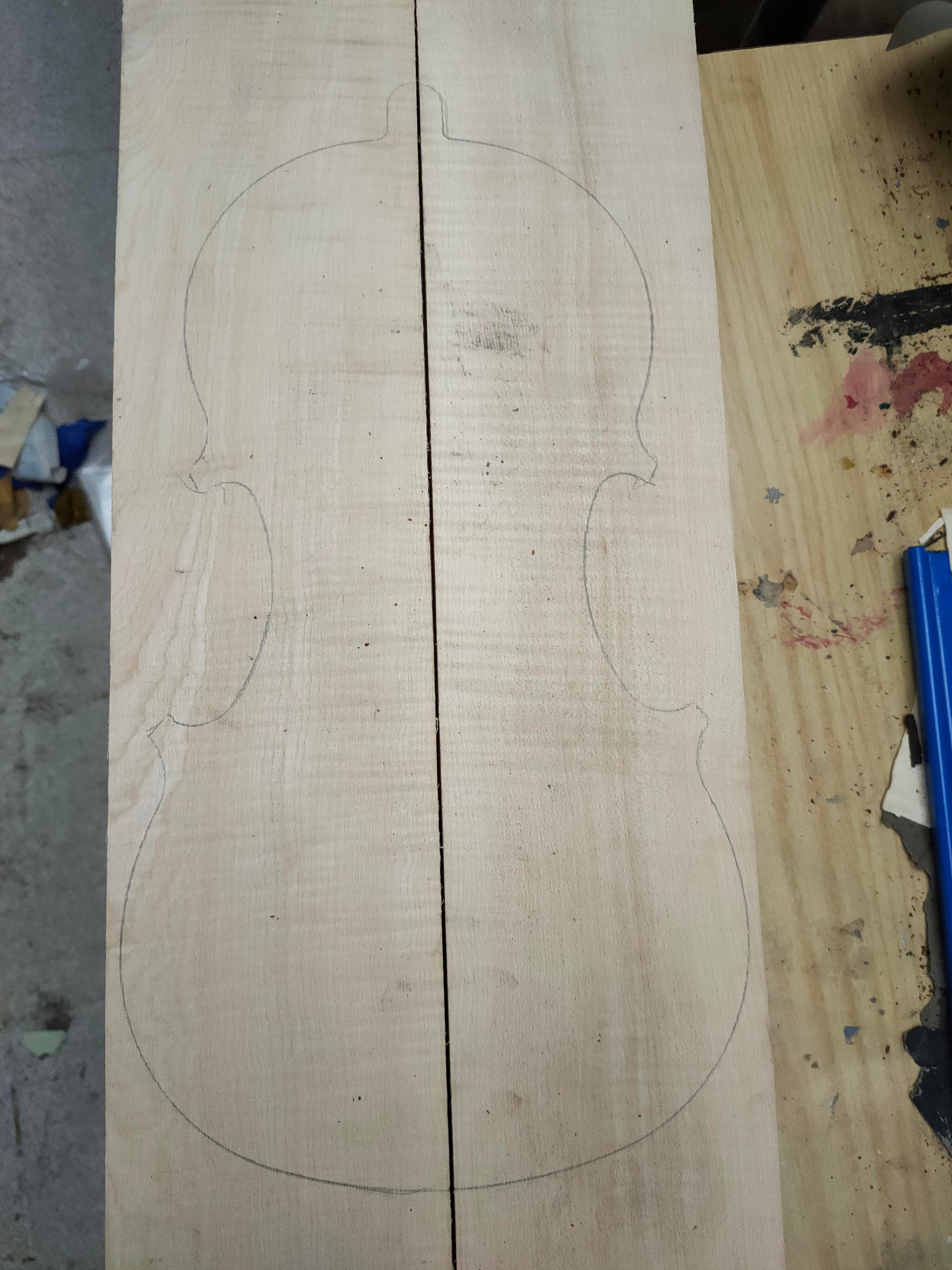 The outline of a violin traced in pencil on raw wood