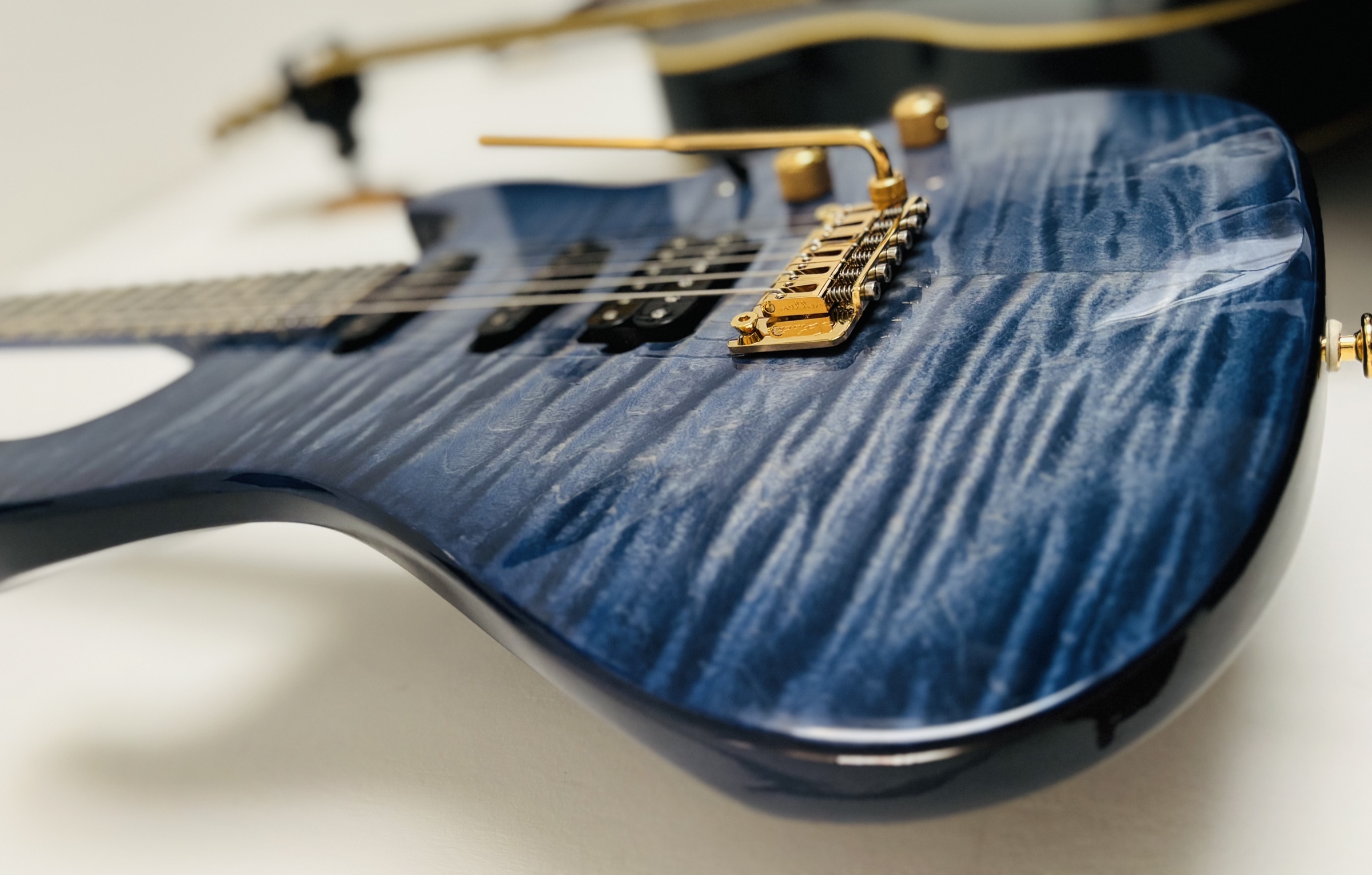 The bridge and the quilted maple top of a finished instrument, with gold hardware