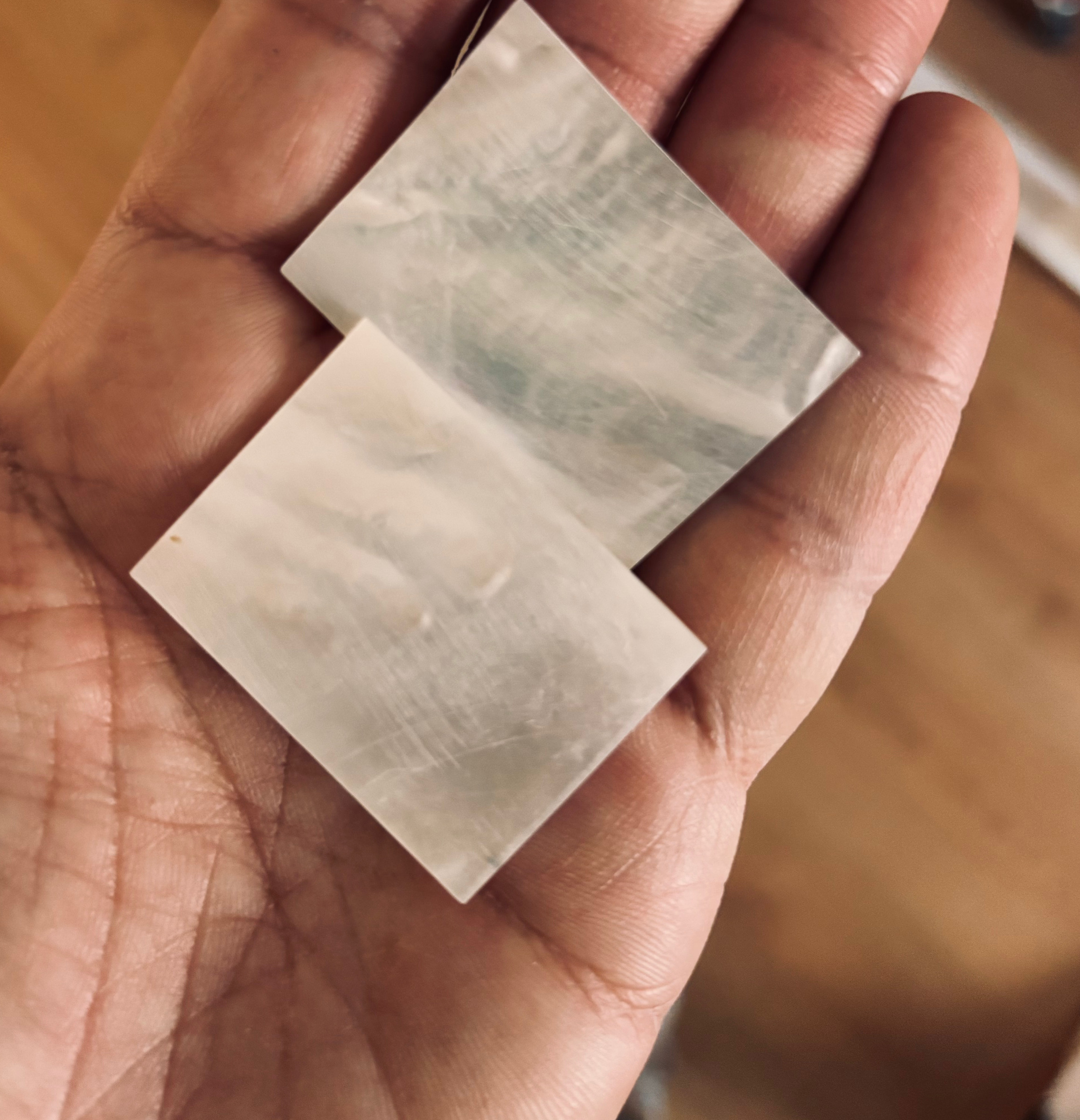 Two small sheets of mother-of-pearl in the luthier's hand