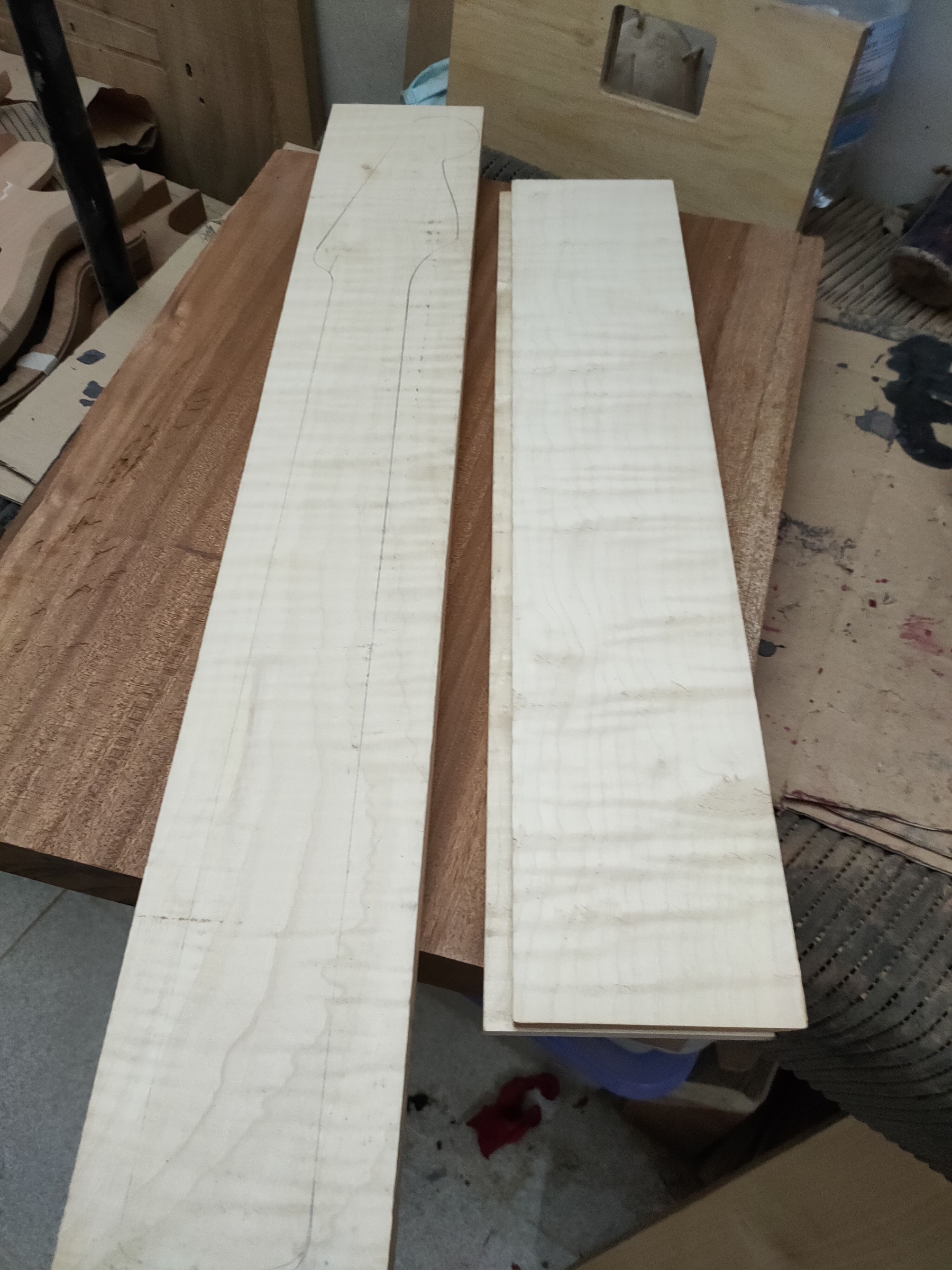 Two flamed maple boards, one with the neck already traced in pencil