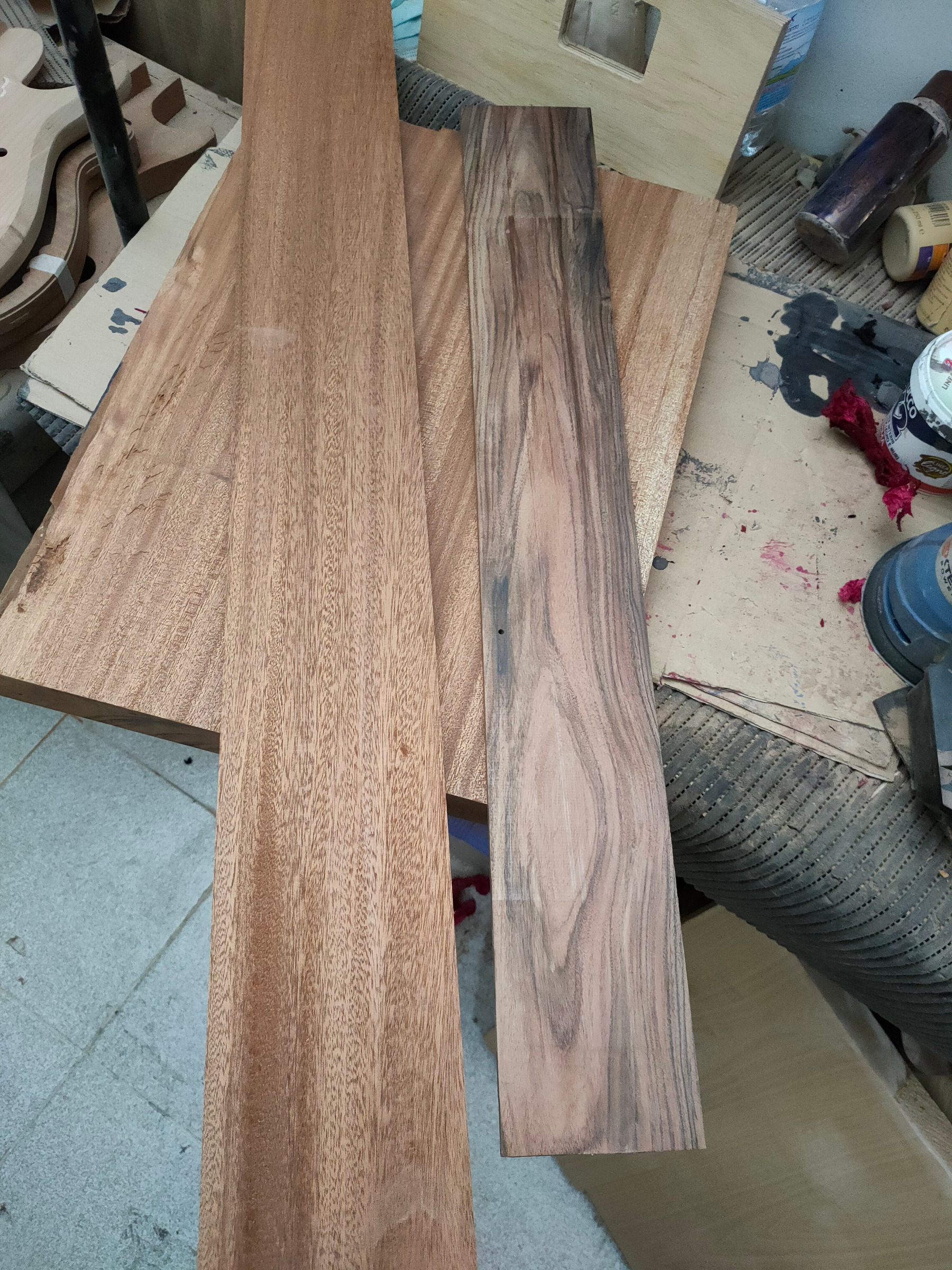 Two long boards of different woods, side by side on the bench
