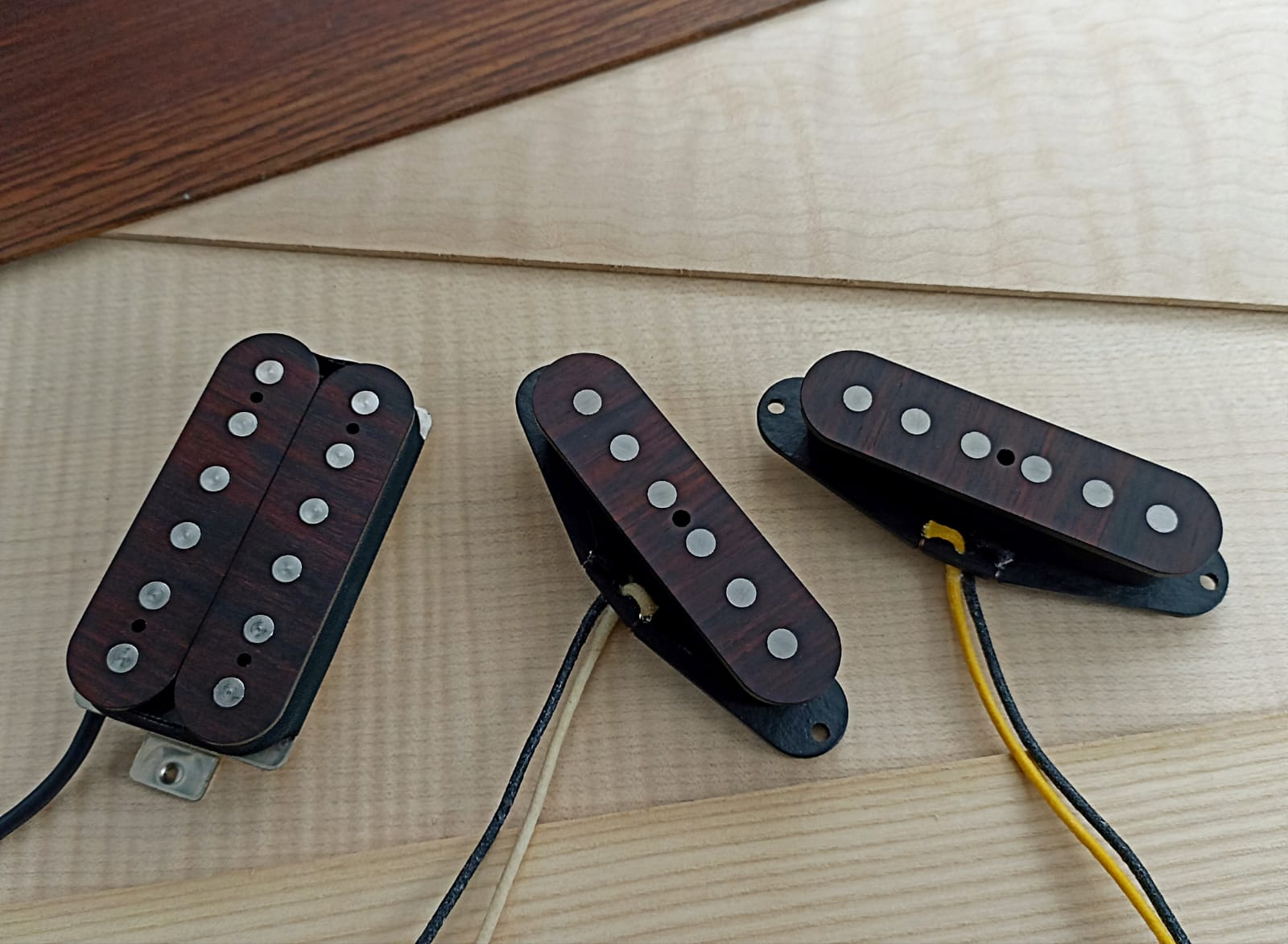 Three pickups with wooden covers, resting on pale wooden boards
