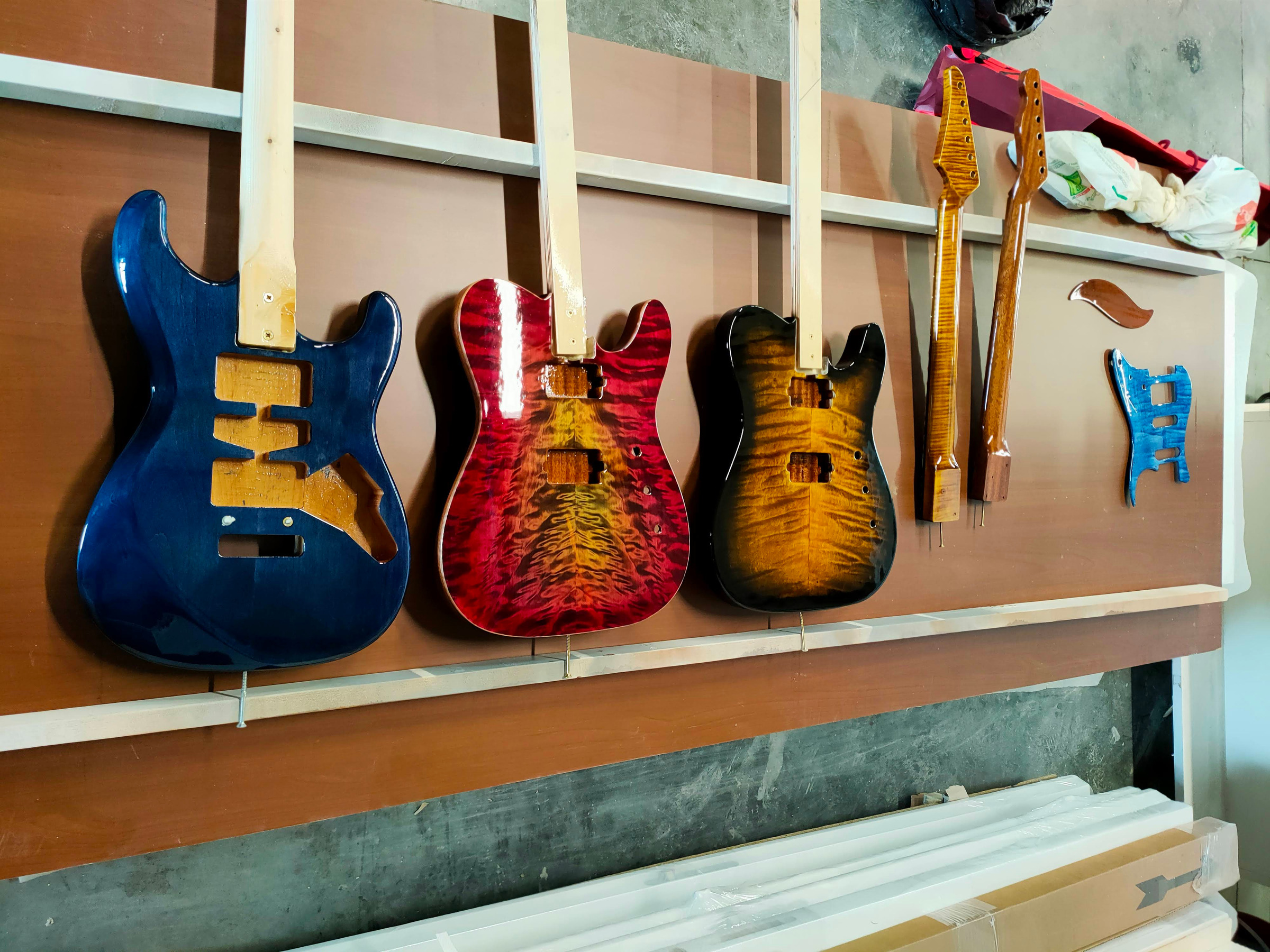Three guitar bodies hanging to dry on a rack, along with two necks